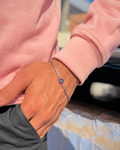 Person wearing a pink sweater with a silver bracelet featuring a blue stone.