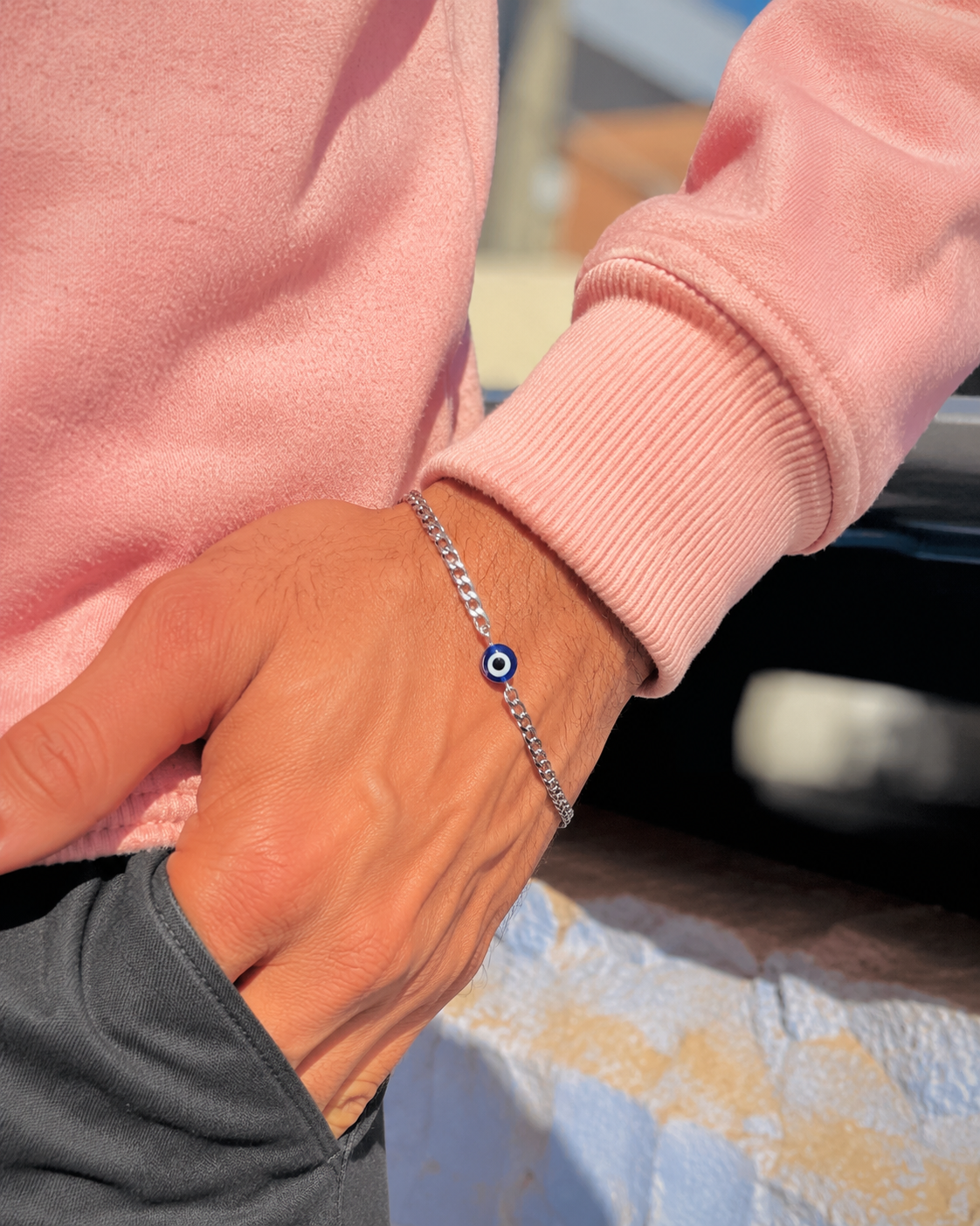 Person wearing a pink sweater with a silver bracelet featuring a blue stone.