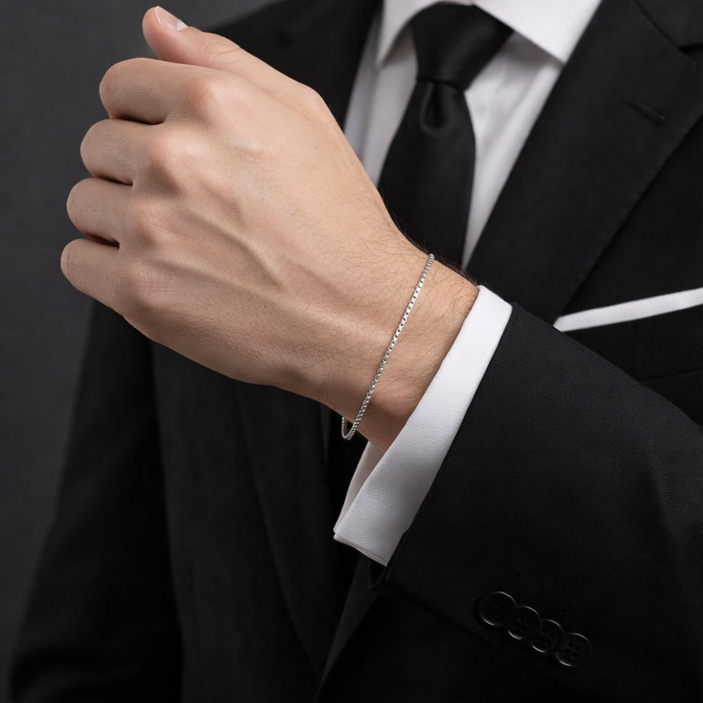 Close-up of a person wearing a silver bracelet with a black suit and white shirt.