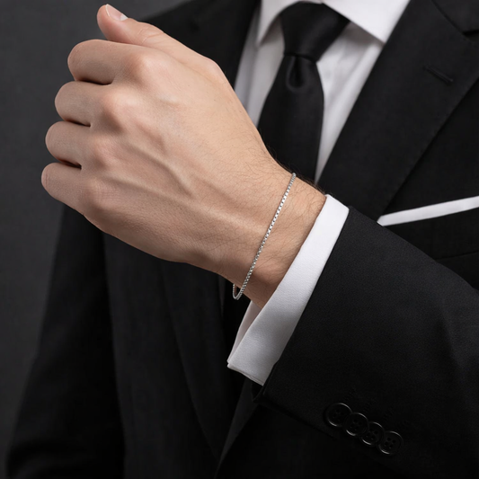 Close-up of a person wearing a silver bracelet with a black suit and white shirt.